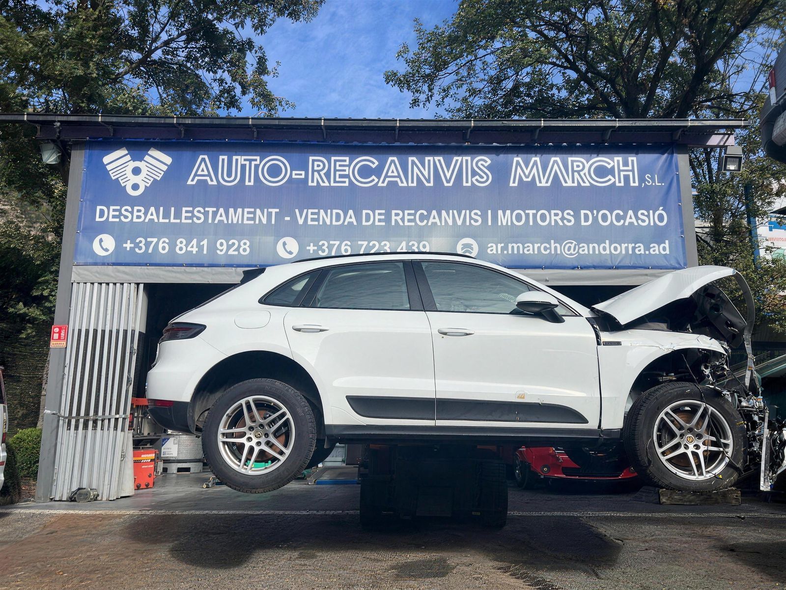 La façana del desballestament d'Auto-Recanvis March a Santa Coloma, amb un Porsche accidentat aixecat amb la carretilla