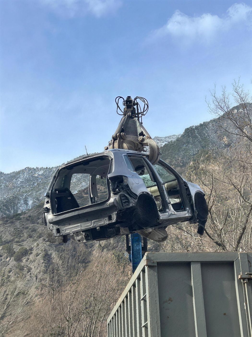 La pinça aixecant la carrosseria d'un cotxe sobre un contenidor